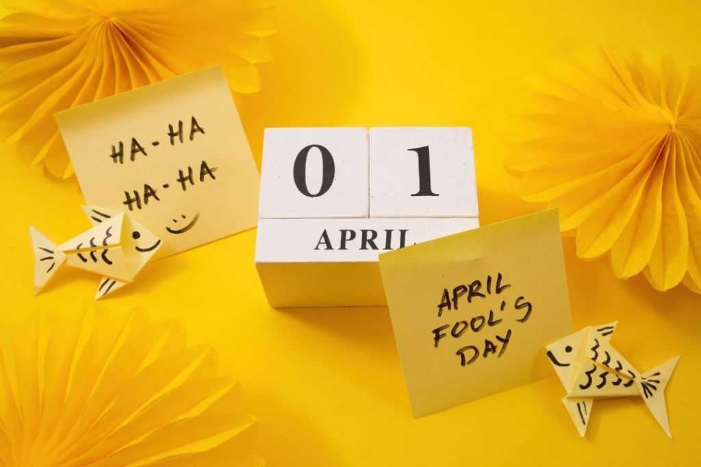 April 1 calendar with a yellow background and festive flowers and origami and sticky notes that say Haha April Fools' Day