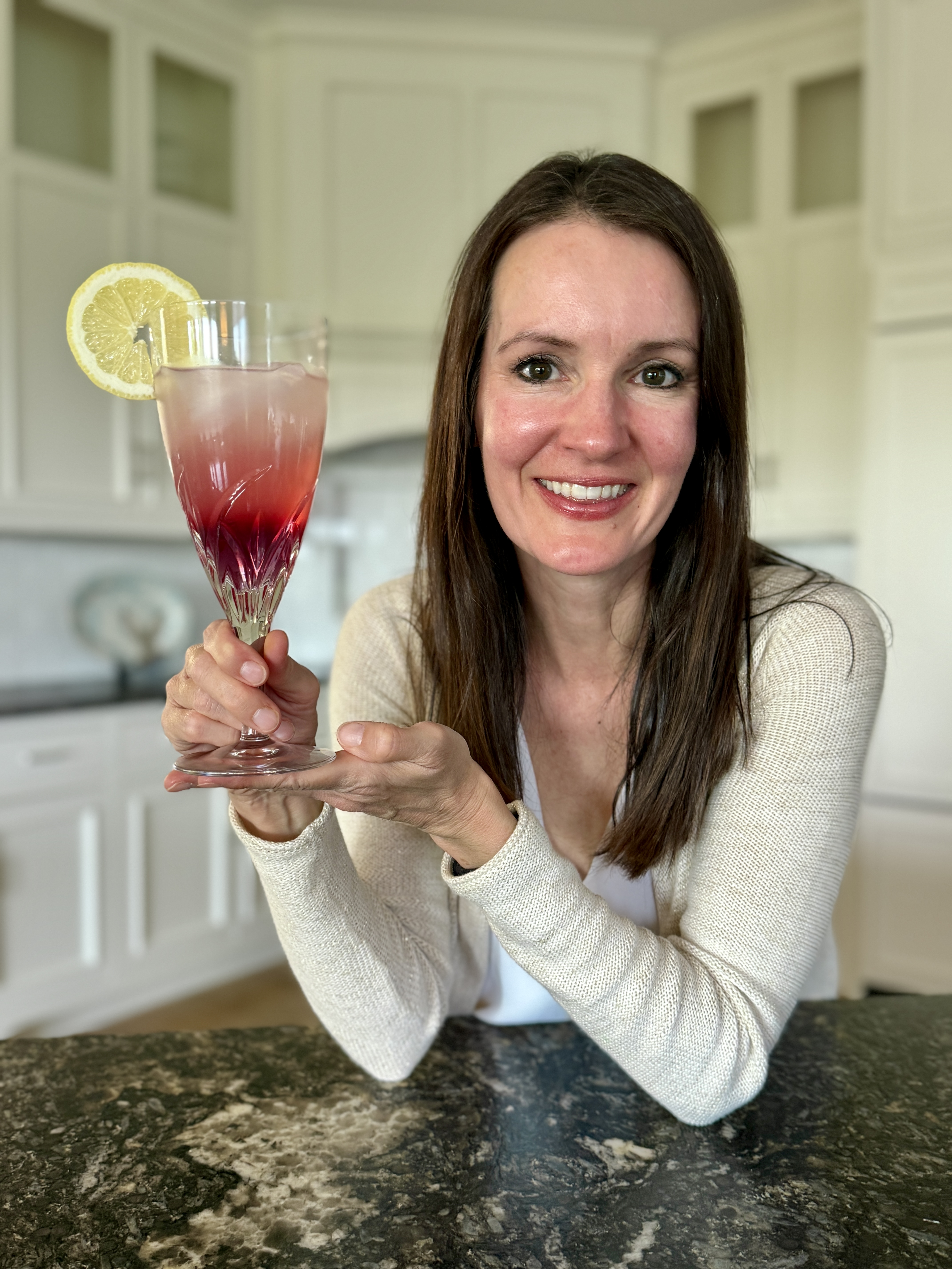 Lauren holding a glass of color-changing lemonade with a lemon garnish