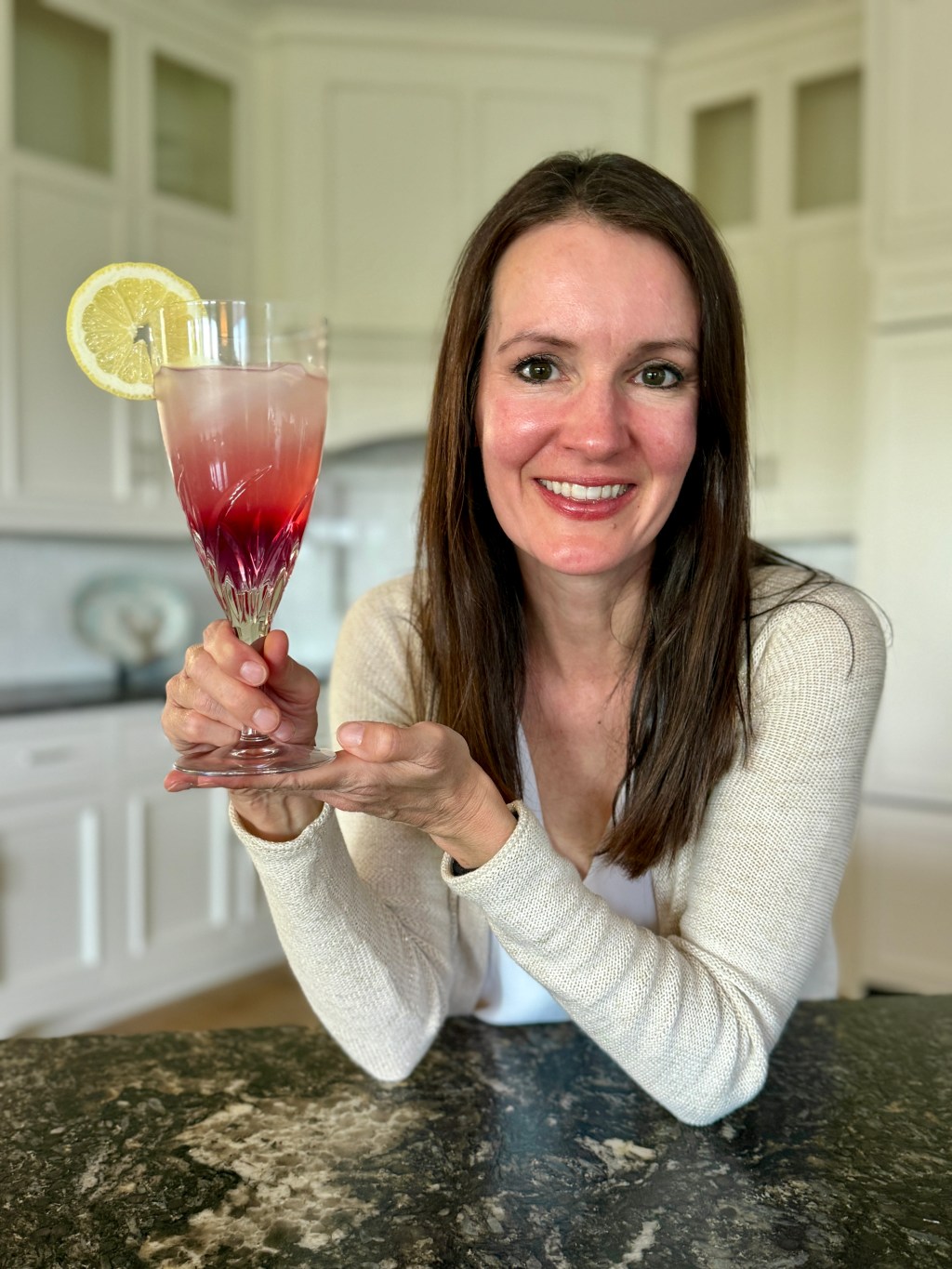 Lauren holding a glass of color-changing lemonade with a lemon garnish