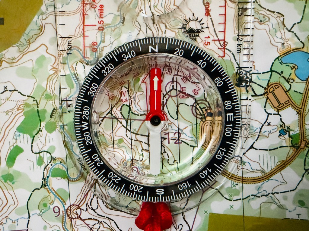A baseplate compass resting on a topographical map.