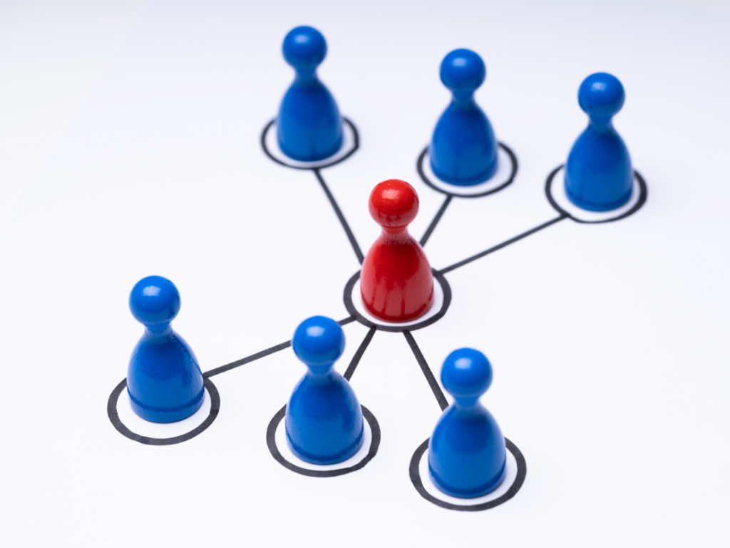 A red game piece surrounded by 6 blue game pieces to symbolize delegation.