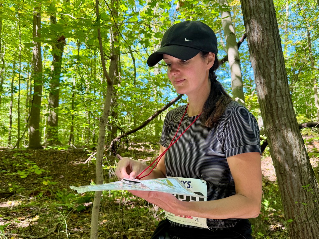 A woman navigating in the woods with a compass and map